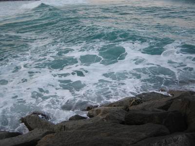 Teal waves breaking against dark rocks